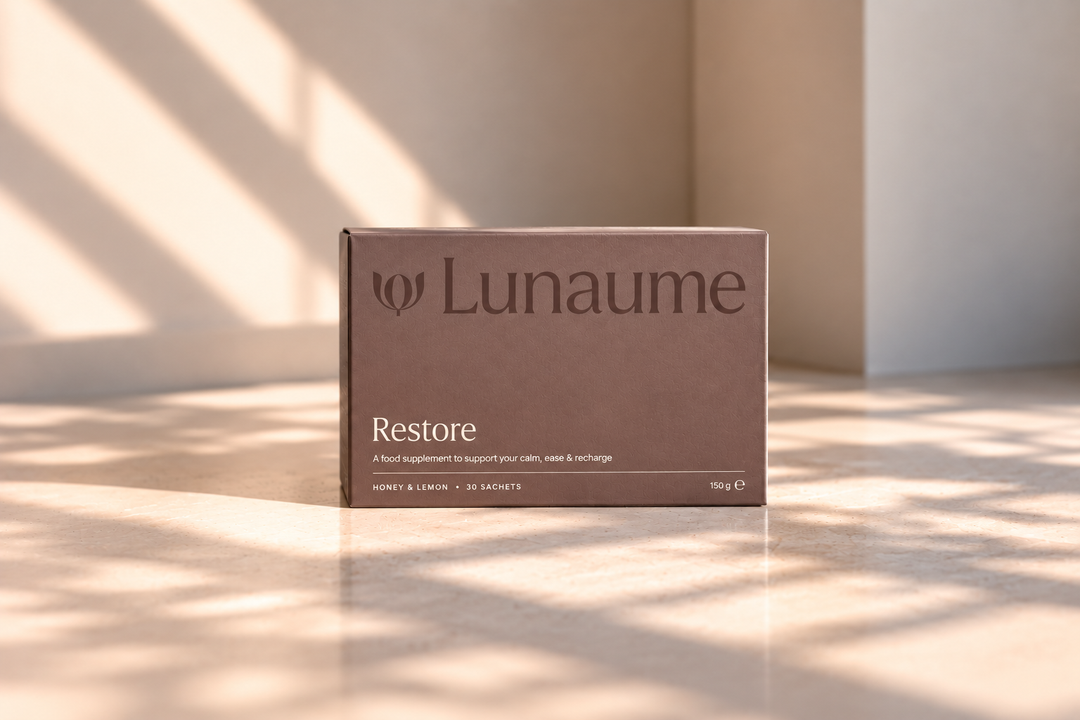 A brown rectangular product box labeled 'Lunaume Restore' sits on a light surface in a softly lit interior with warm sunlight and shadows.